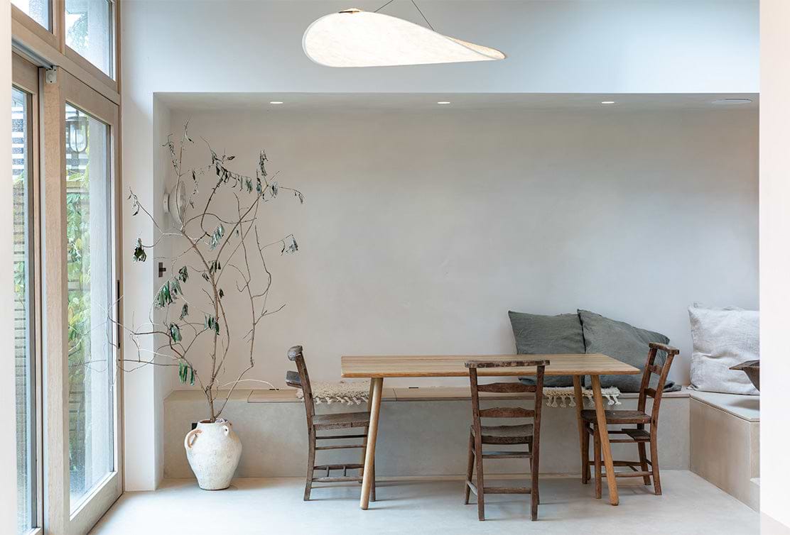 Bright sunny dining room with a white interior, featuring a wooden dining set and potted plant