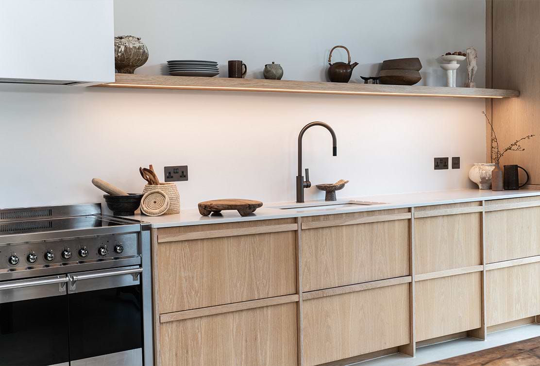Kitchen setting with an open shelving unit, wooden cabinets and a bronze kitchen sink