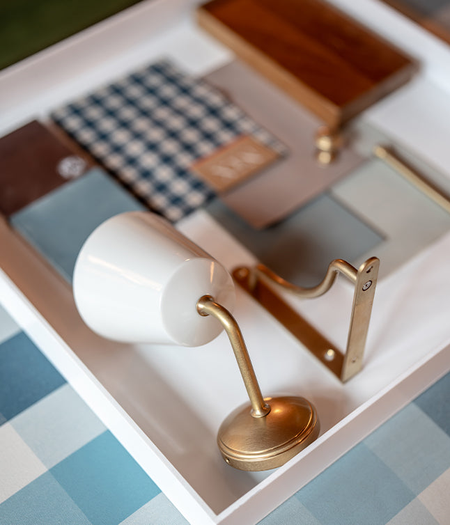 Stylish arrangement of fabric swatches, wood samples, and metal accents on a white tray, showcasing a design palette.