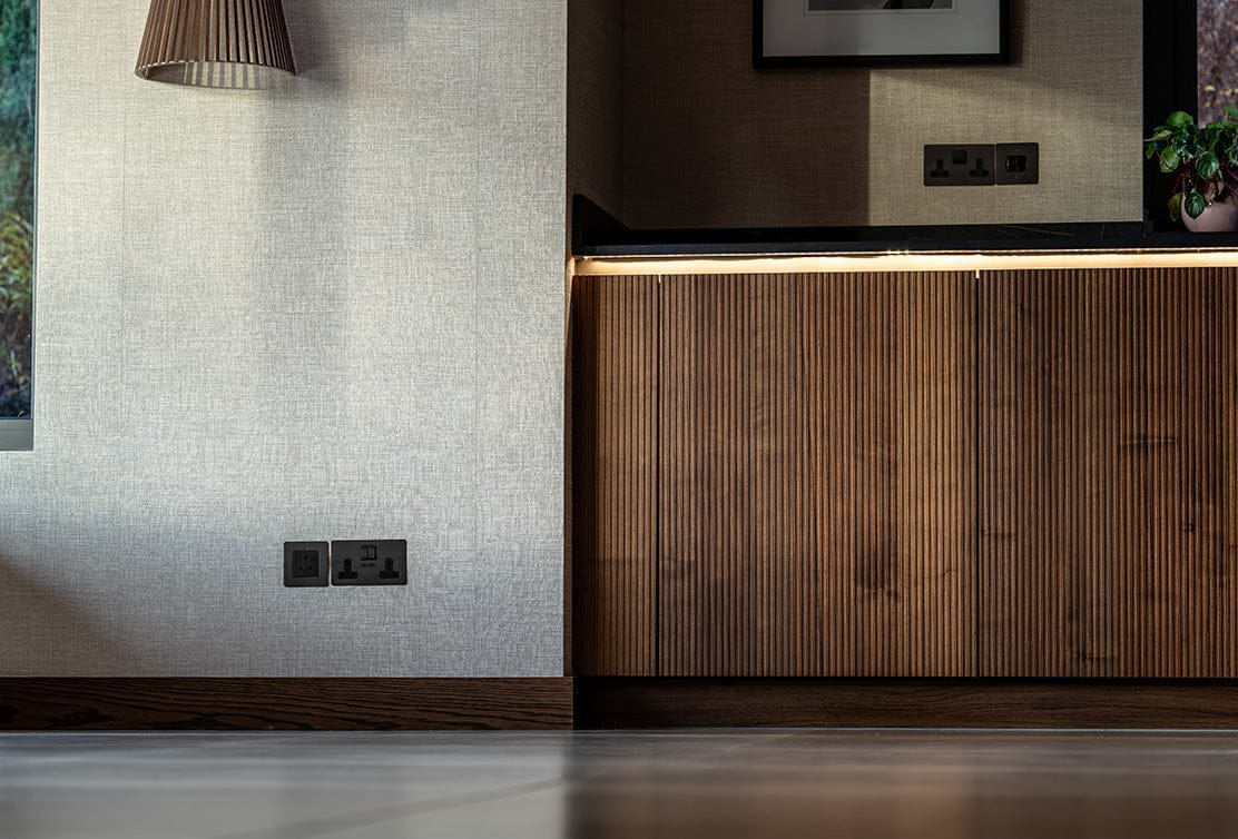 A modern interior with a textured wall, wooden cabinetry, and stylish light fixture, showcasing sleek design and elegance.
