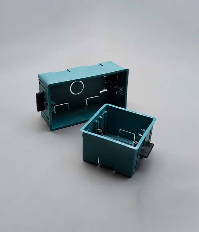 Two teal plastic electrical boxes, one larger and one smaller, displayed against a gray background, showing internal mounting clips.