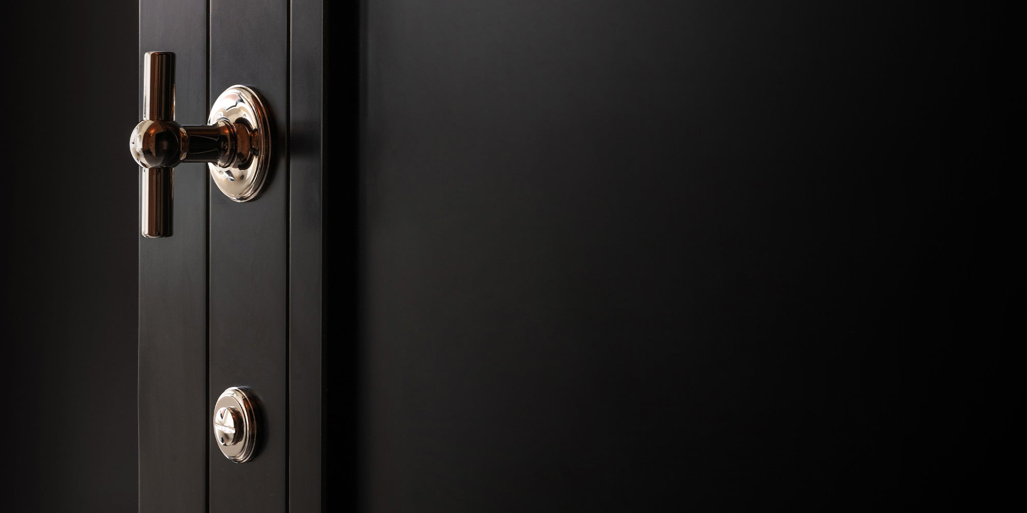 Close-up of a sleek black door featuring a shiny polished nickel handle and thumb turn, showcasing modern design details.