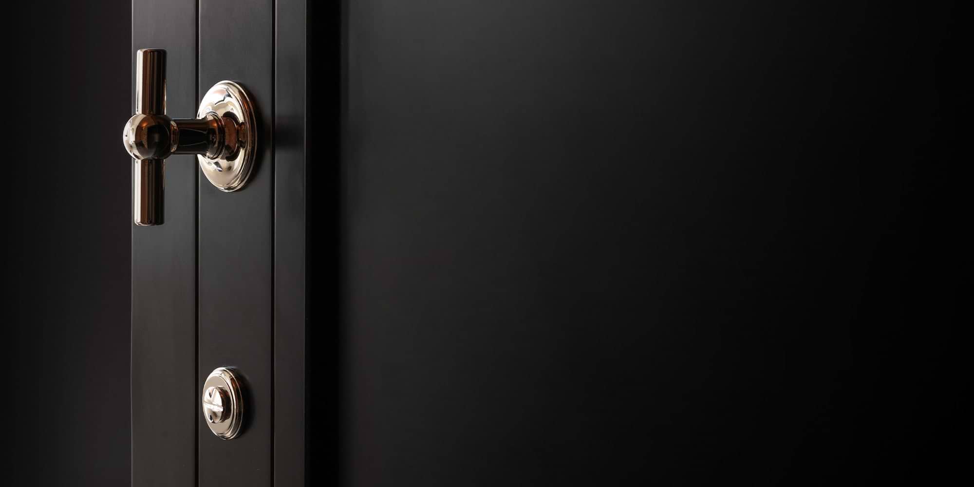 Close-up of a sleek black door featuring a shiny polished nickel handle and thumb turn, showcasing modern design details.
