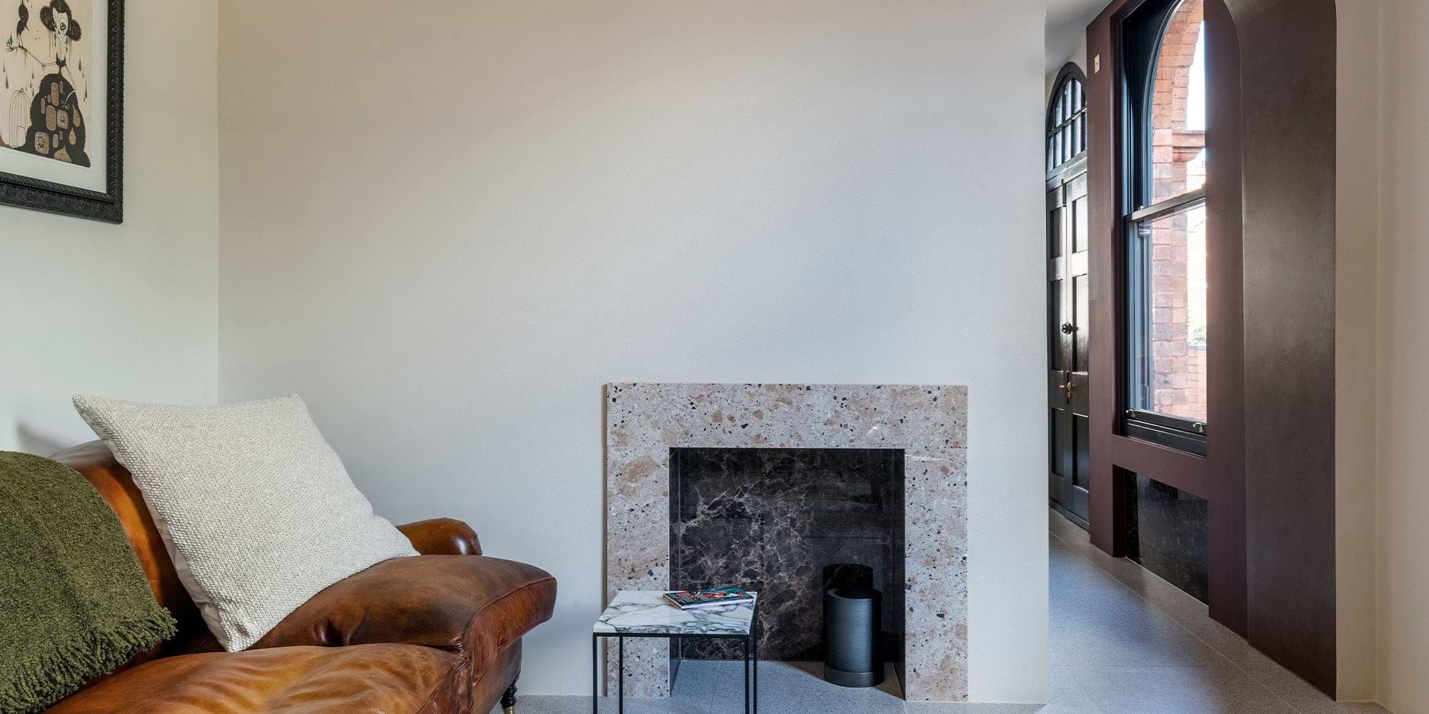 Cozy living space featuring a leather sofa, marble-topped side table, and a minimalist fireplace with light-colored decor.