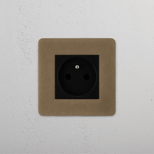 Antique brass black French power module on a beige plate, mounted on a white wall for elegant integration.
