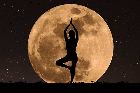 woman doing yoga in front of the moon