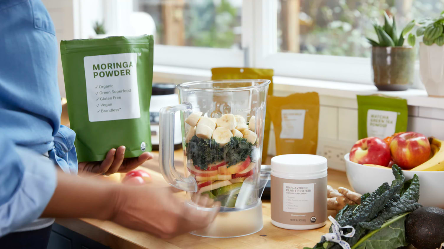 A woman puts greens powder keto supplements into a blender