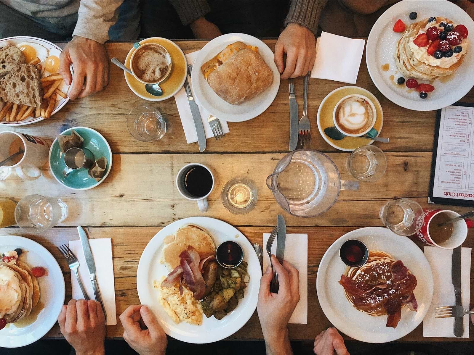 Best digestive enzymes: overhead view of people sitting at a table with plates of many different kinds of food