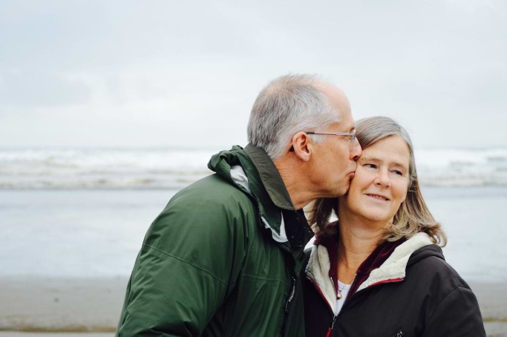 Menopause and anxiety: An older man kisses an older woman on the cheek as she looks away