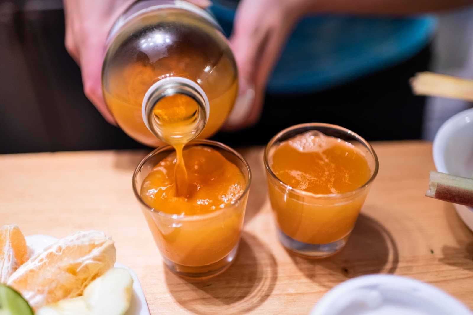 Kombucha side effects: Person pouring homemade kombucha into glasses