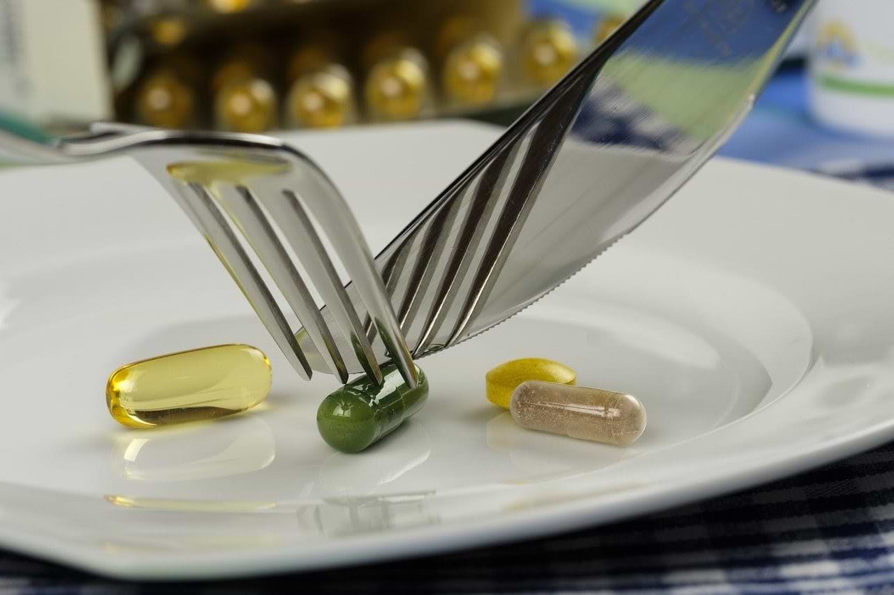 Best digestive enzymes: A fork and knife cutting a supplement pill