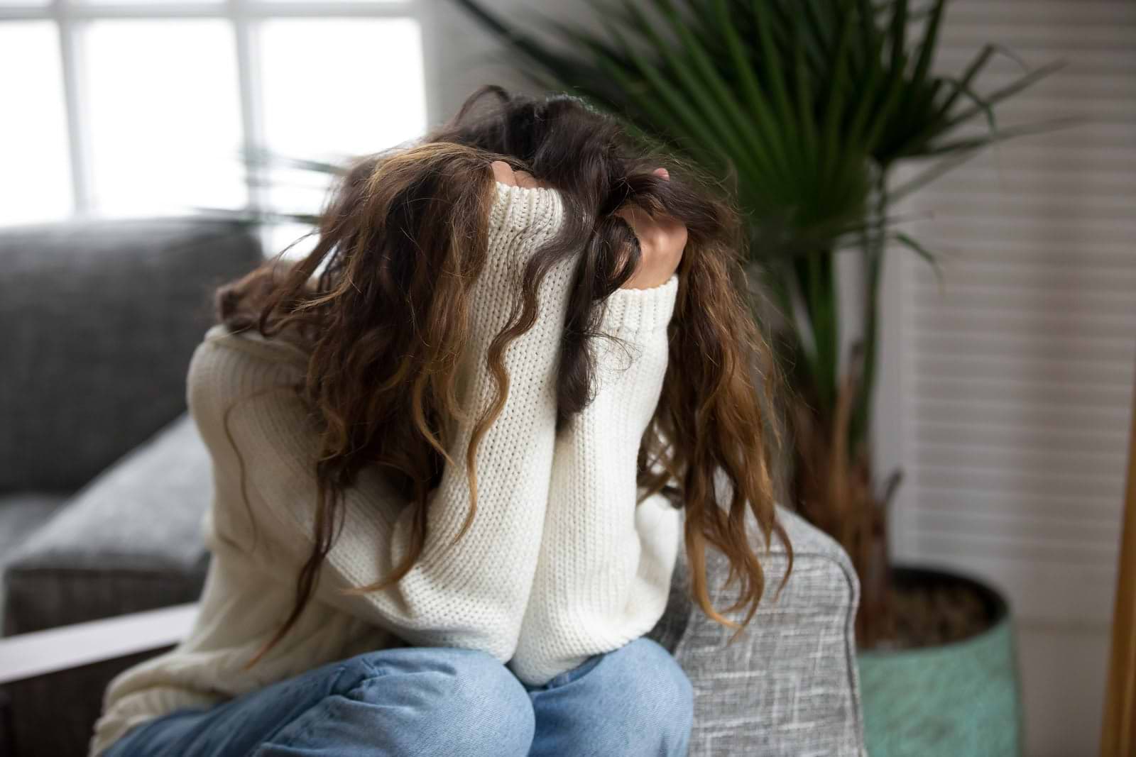 Distressed woman with her face covered and hair falling over