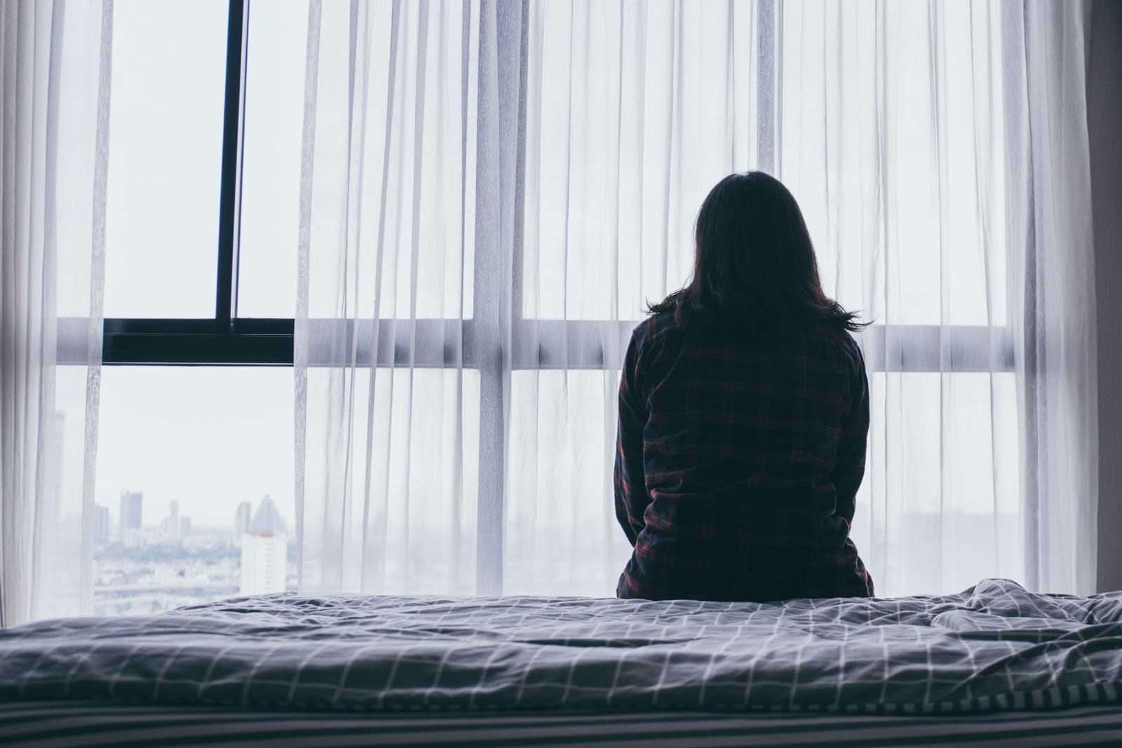IBS and anxiety: Silhouette of woman looking outside her window