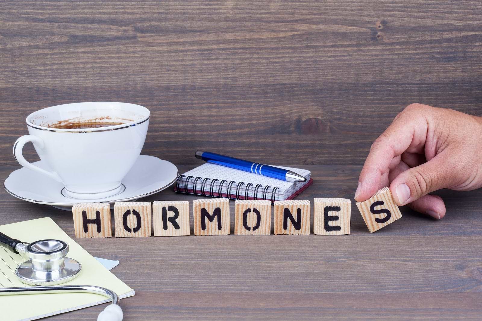 Low Progesterone Symptoms: Wood tiles spelling out the word "hormones"