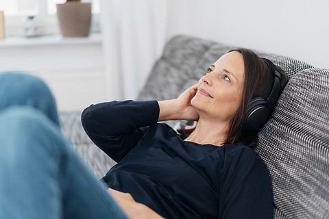 Woman listening to a podcast on a PMS app