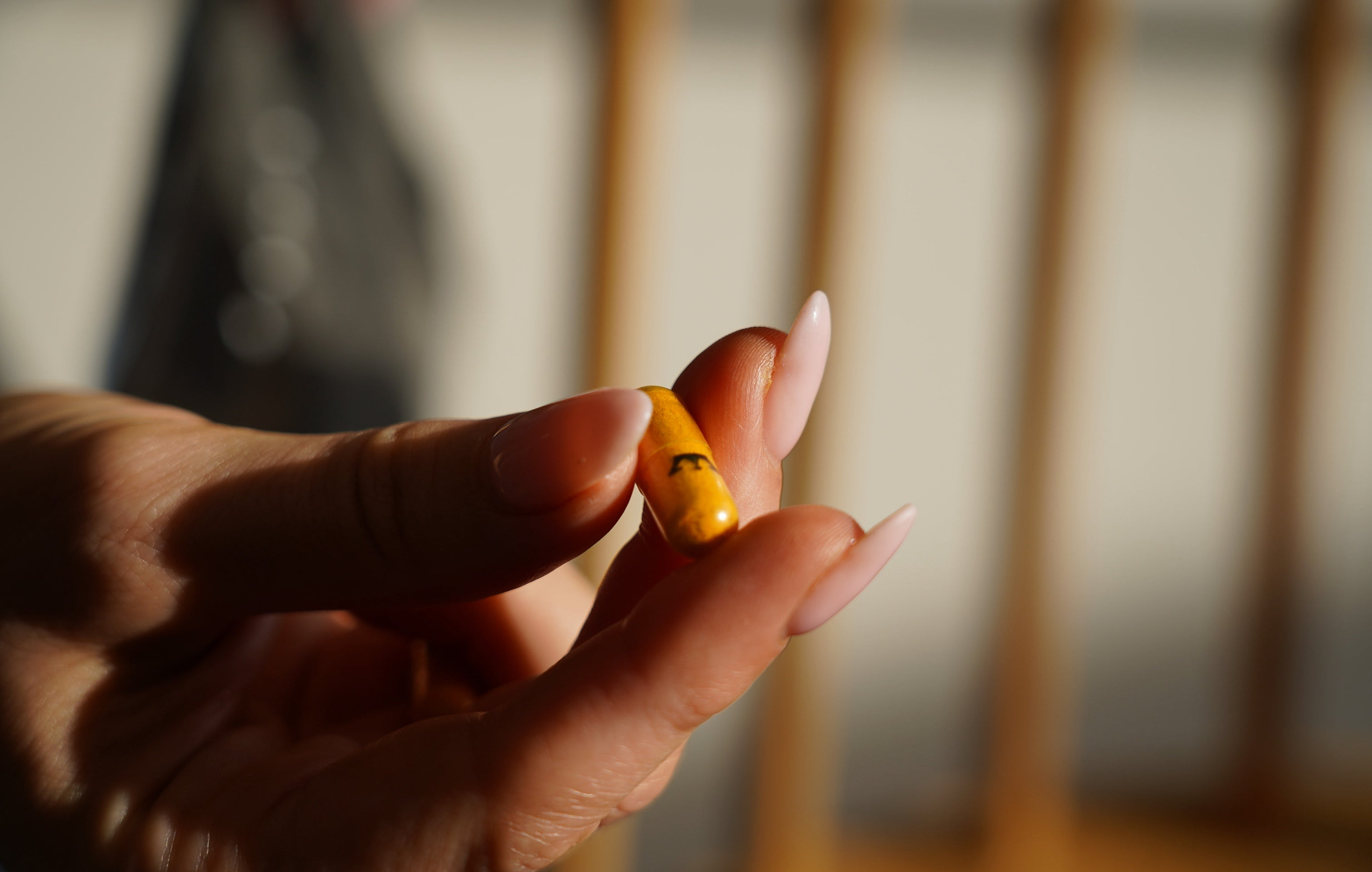 Hand holding LYMA Supplement yellow capsule
