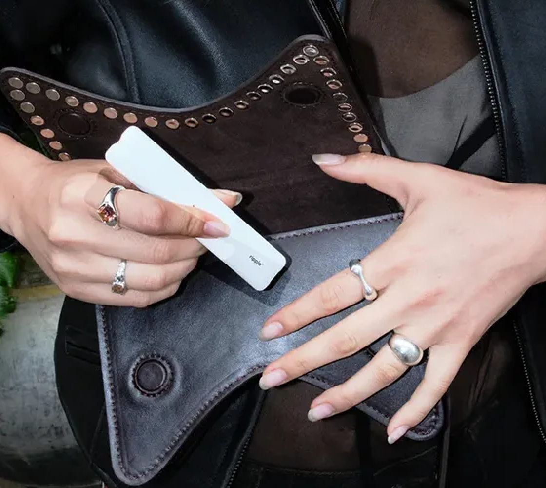 Hands holding a ripple⁺ device over a leather bag