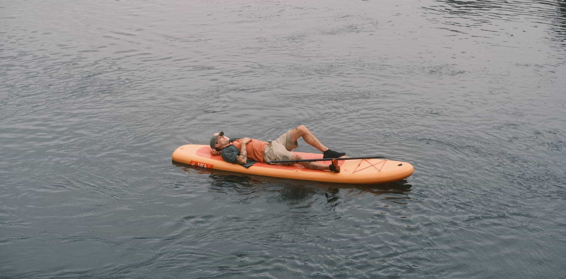 A man relaxing on an orange paddleboard on calm water in the Sealskinz Father's Day Gift Guide 2026.