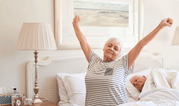 A man waking up rested and stretching after a full night of sleep