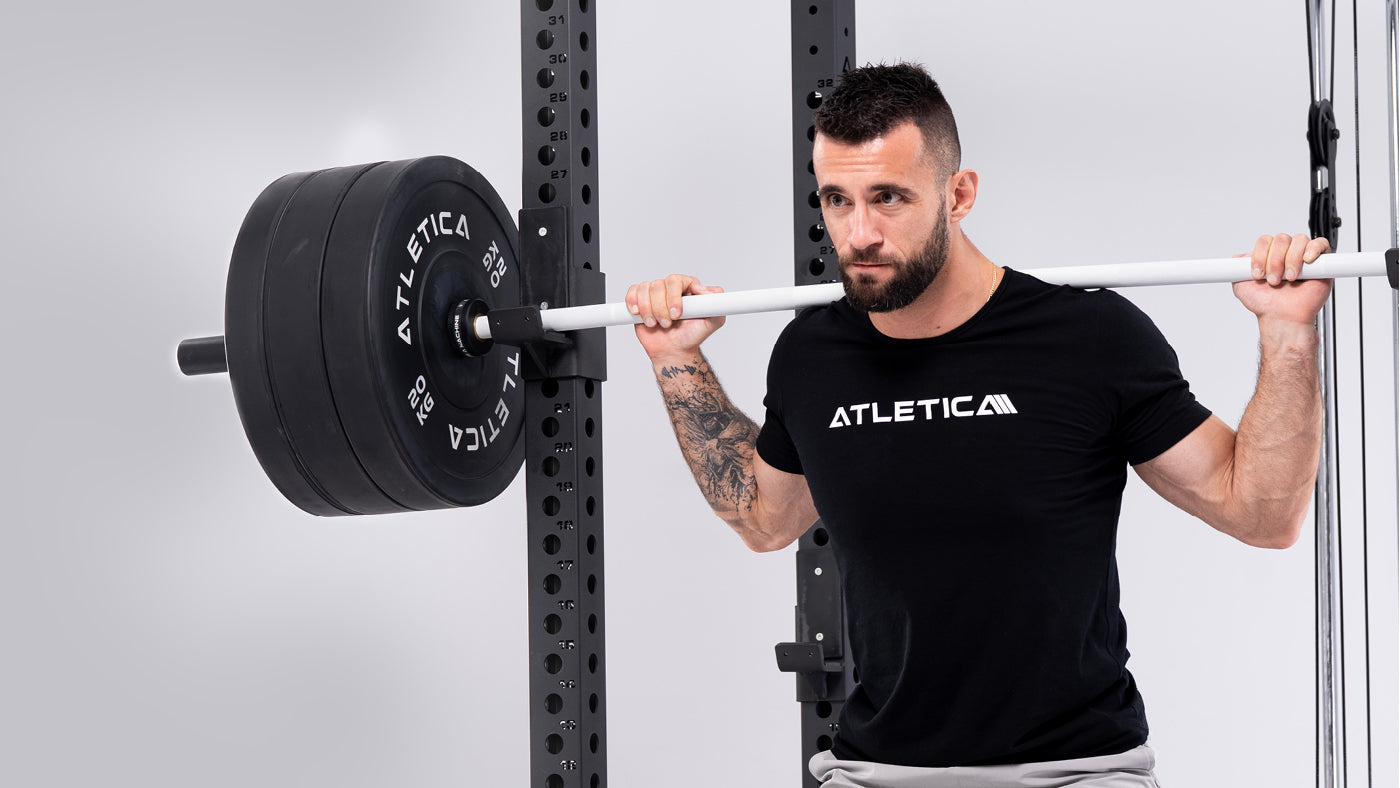 Back Squat am R8 Blackhawk Power Rack mit weißer Stange und schwarzen Bumper Plates
