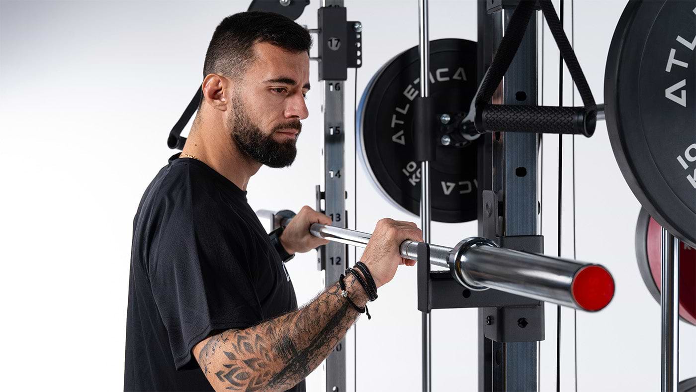 Athlet nimmt eine Atletica Hantelstange vom Power Rack