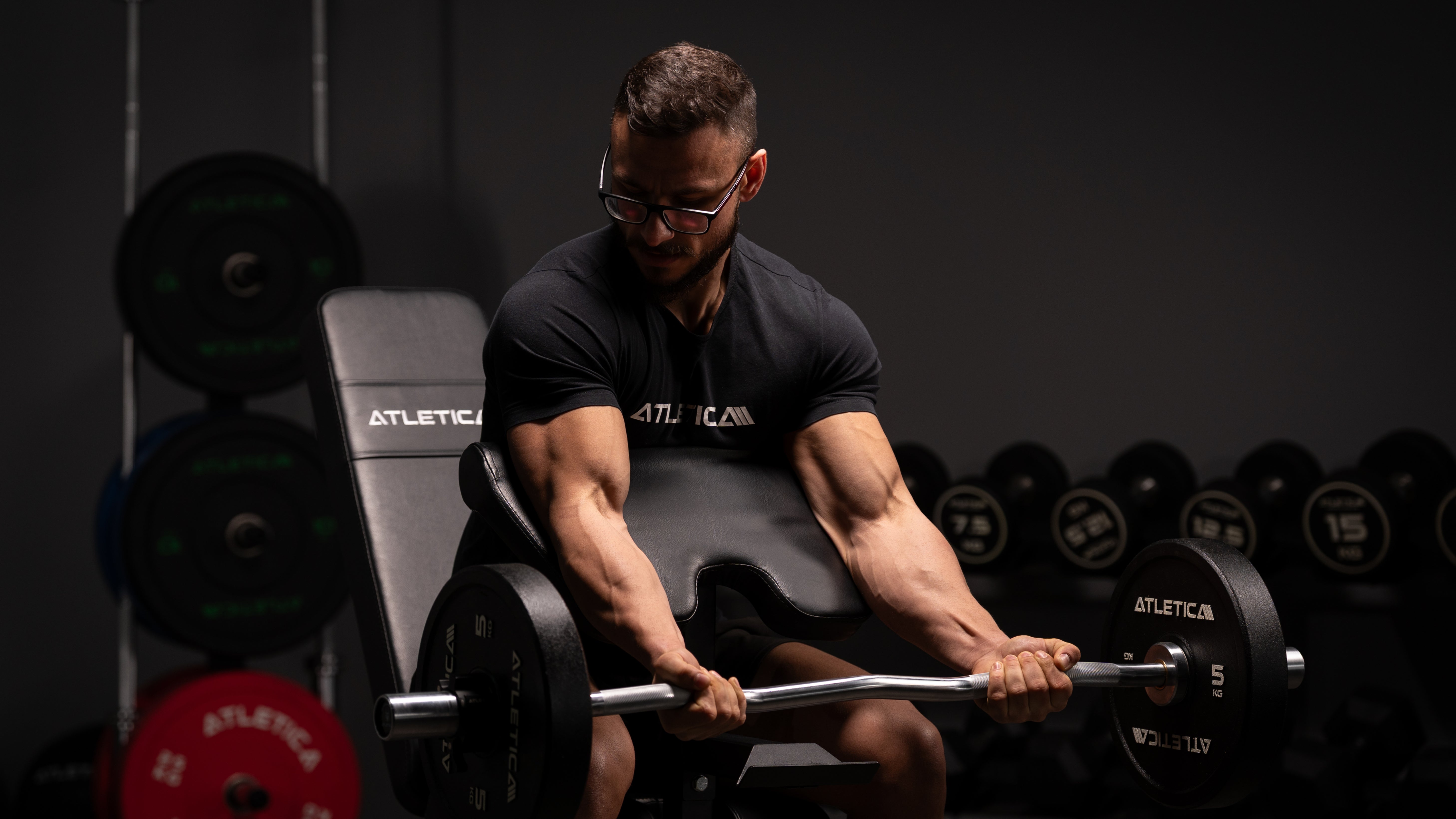 Bizeps Curls auf Atletica verstellbarer Hantelbank mit SZ-Stange mit Bumper Plates