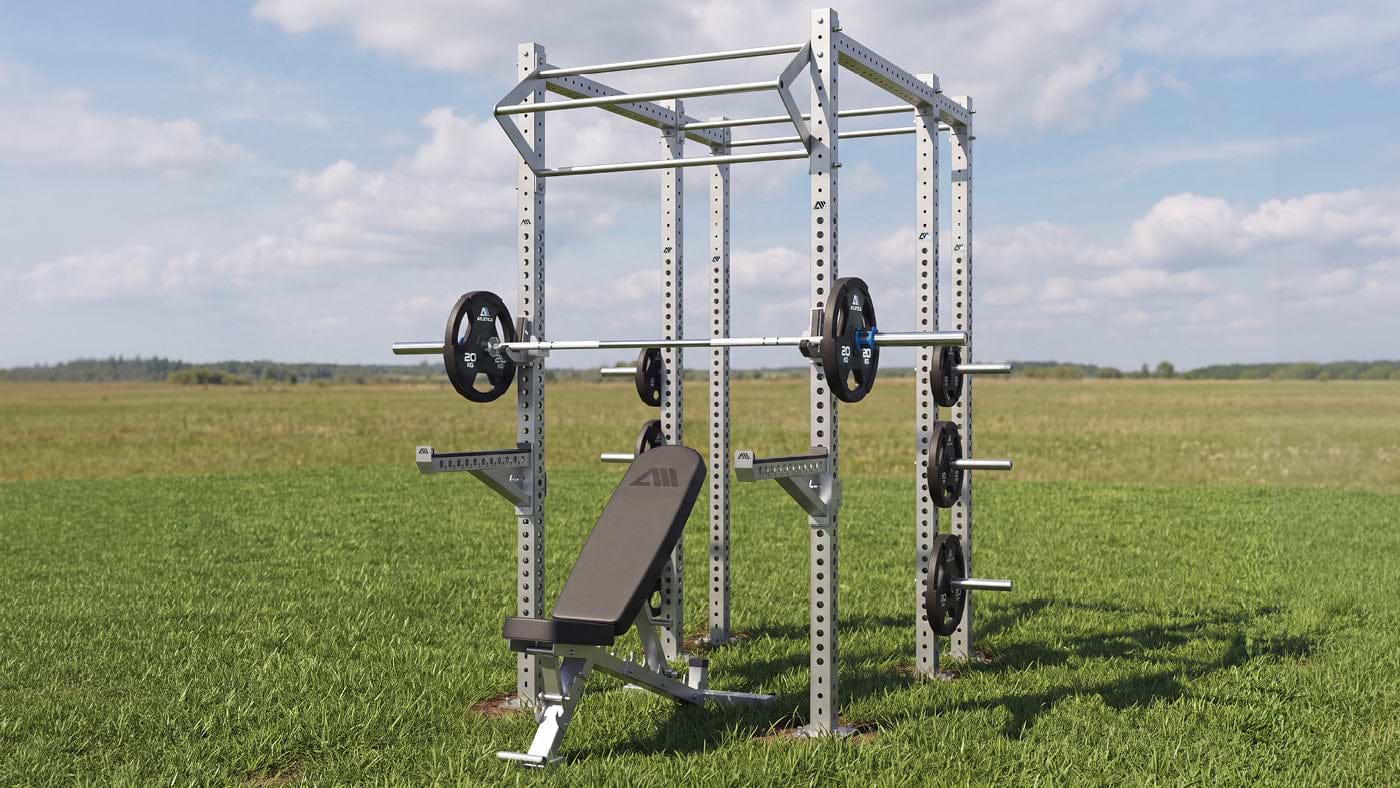 Atletica Outdoor Edelstahl Power Rack mit Inox Langhantel, Onyx Hantelbank und Gripper Plates auf einer Wiese