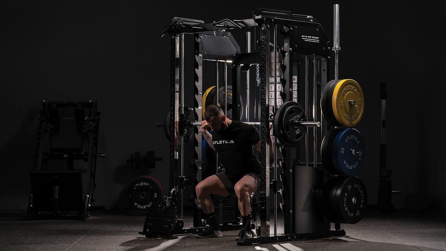 Man performing squats on the Atletica multi-gym with Smith machine