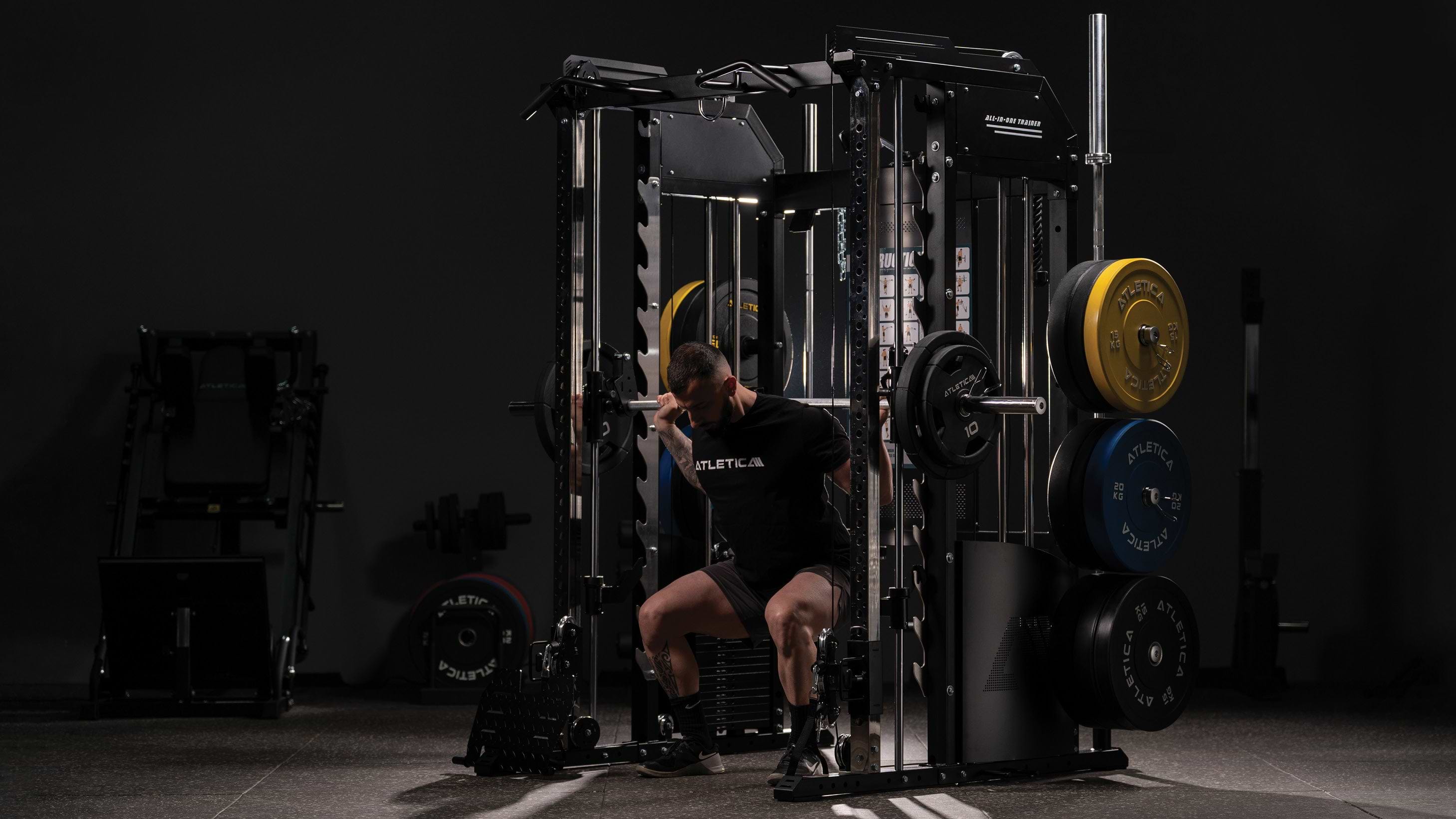 Man performing squats on the Atletica multi-gym with Smith machine