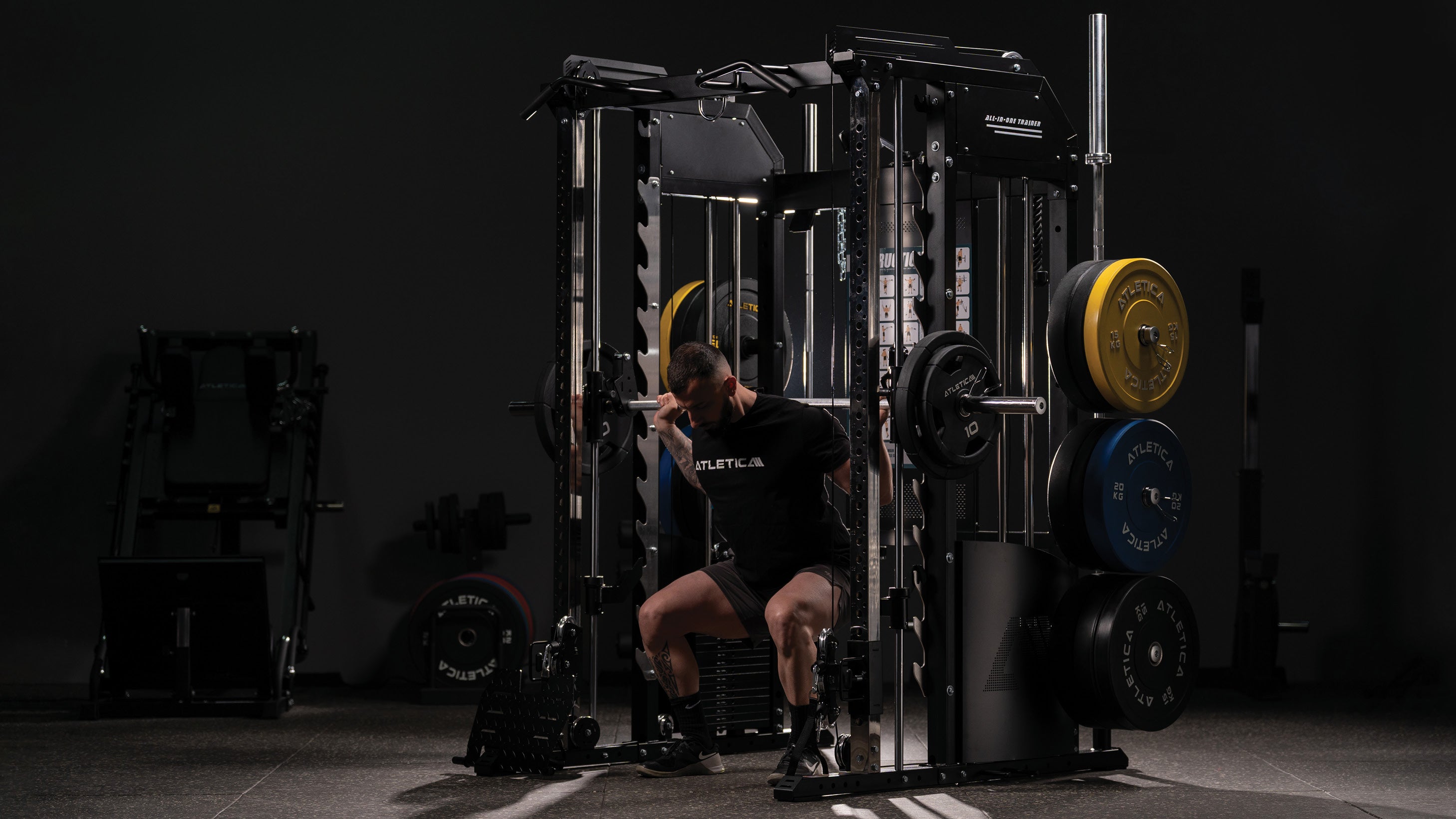 Man performing squats on the Atletica multi-gym with Smith machine