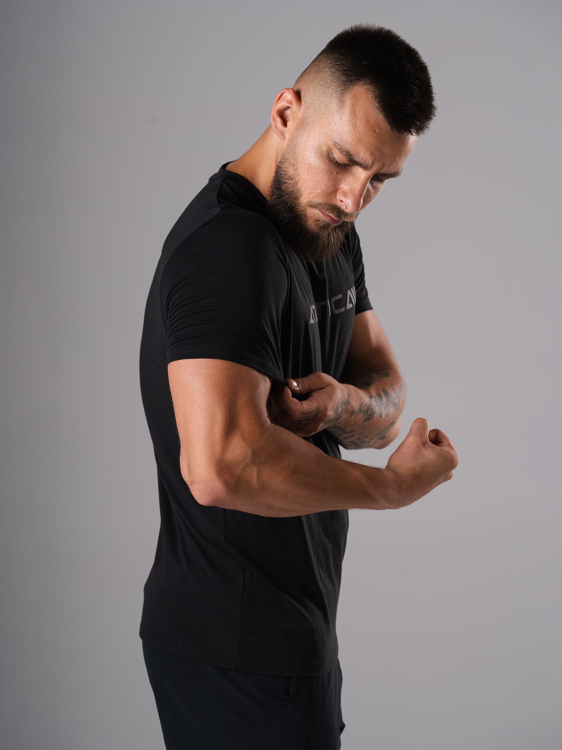 Seitliche Ansicht: Mann im schwarzen Merch Flex Train T-Shirt von Atletica