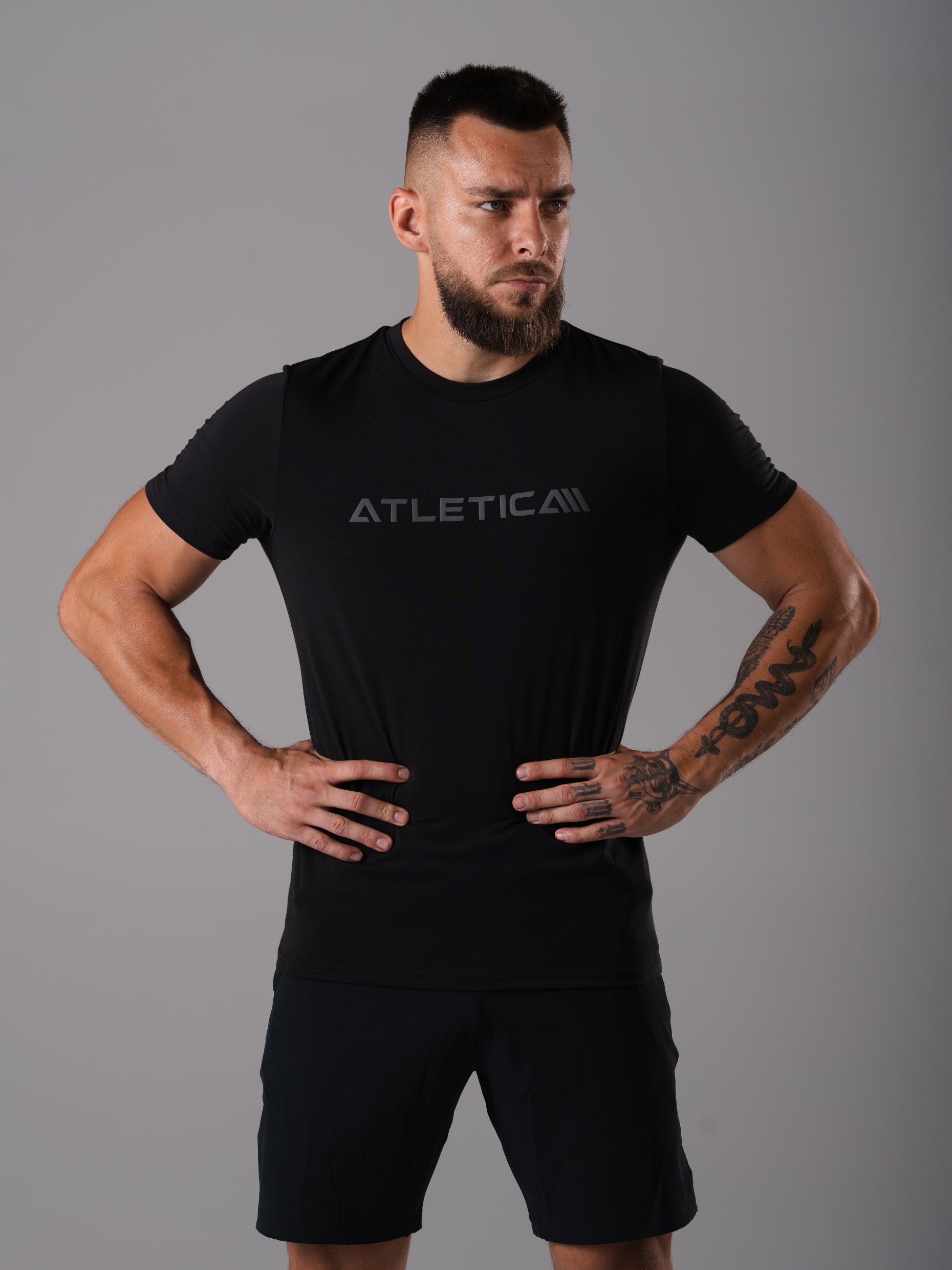 Mann im schwarzen Merch Flex Train T-Shirt von Atletica mit Händen in den Hüften