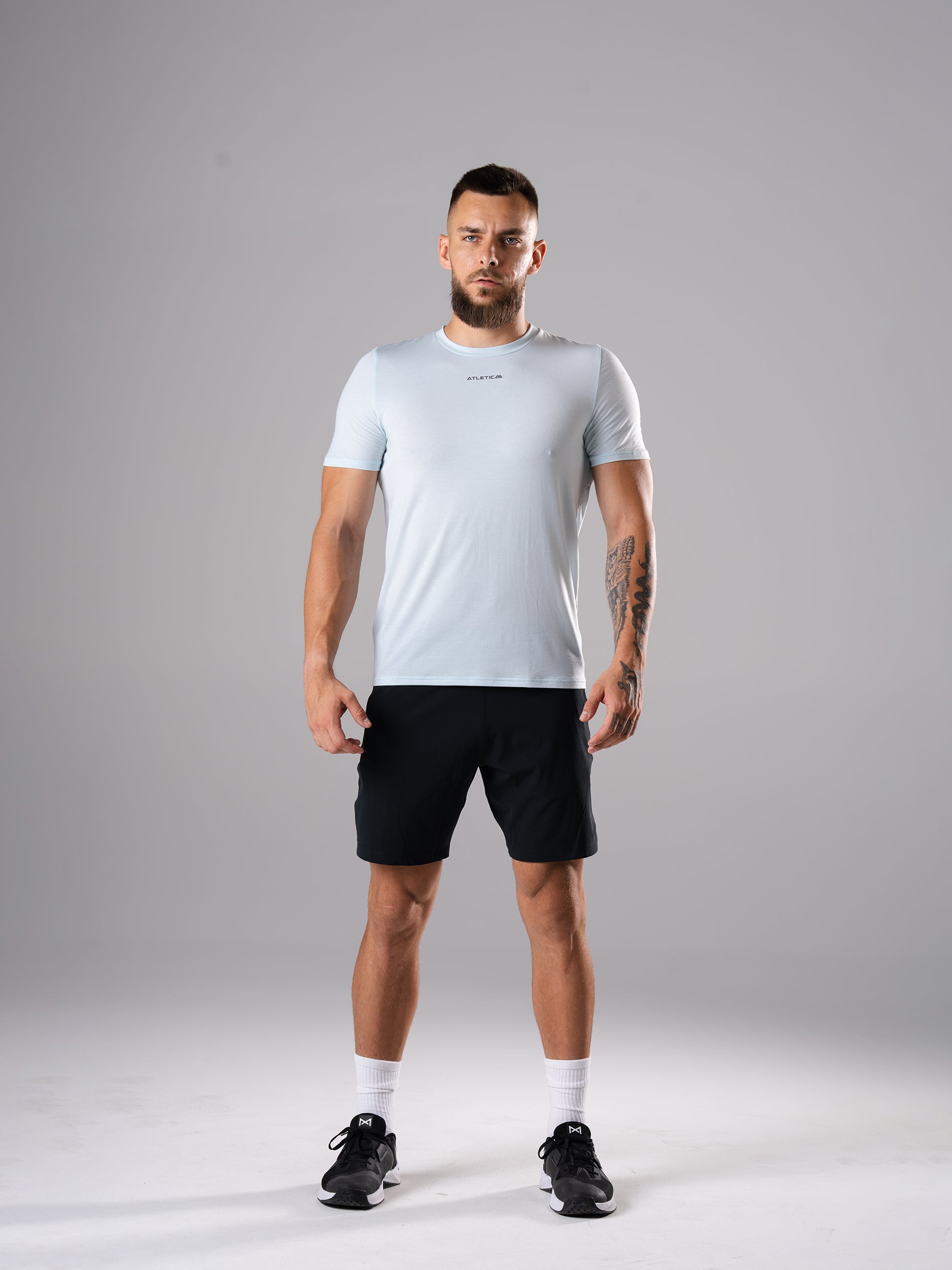 Mann in den Flex Train Shorts in Schwarz von Atletica mit blauem T-Shirt, Ganzkörperansicht