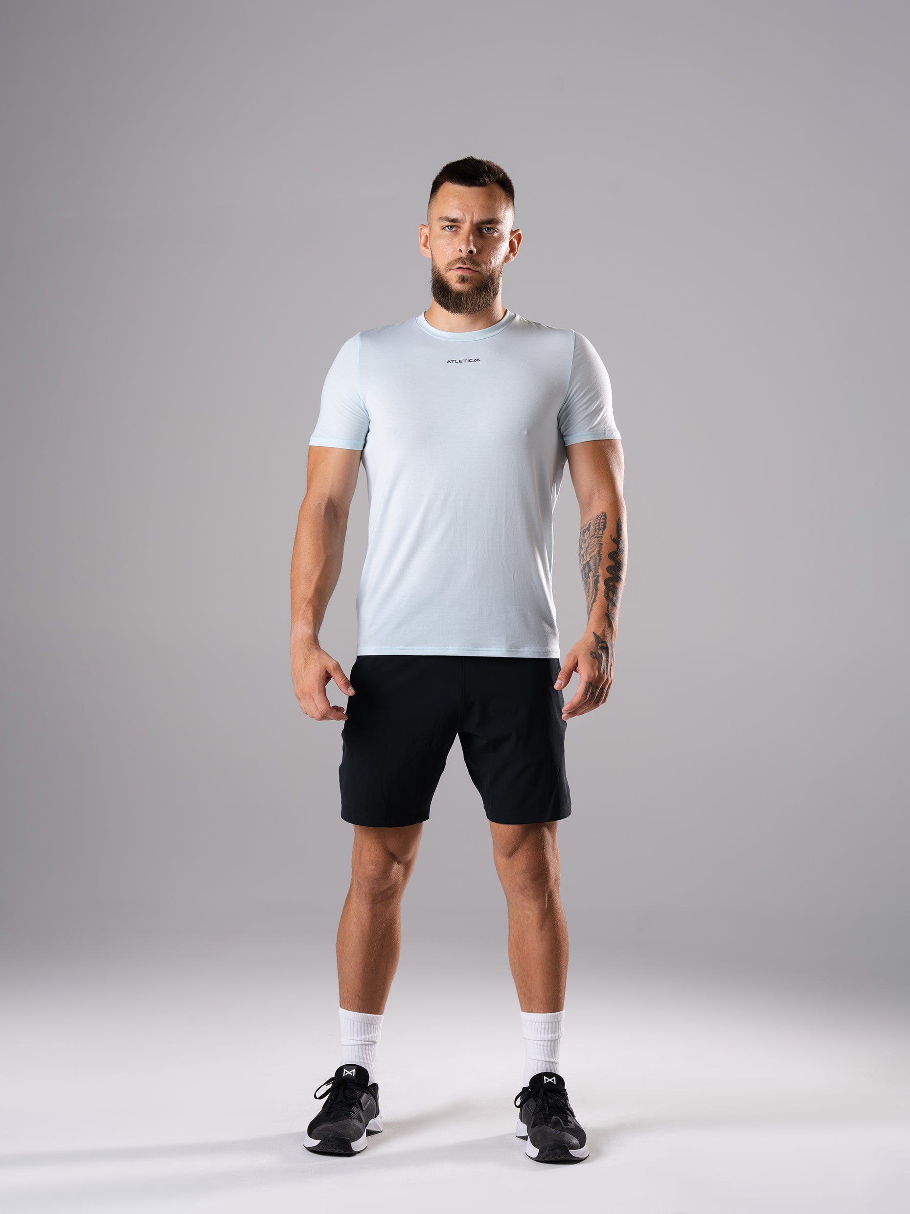 Mann in den Flex Train Shorts in Schwarz von Atletica mit blauem T-Shirt, Ganzkörperansicht