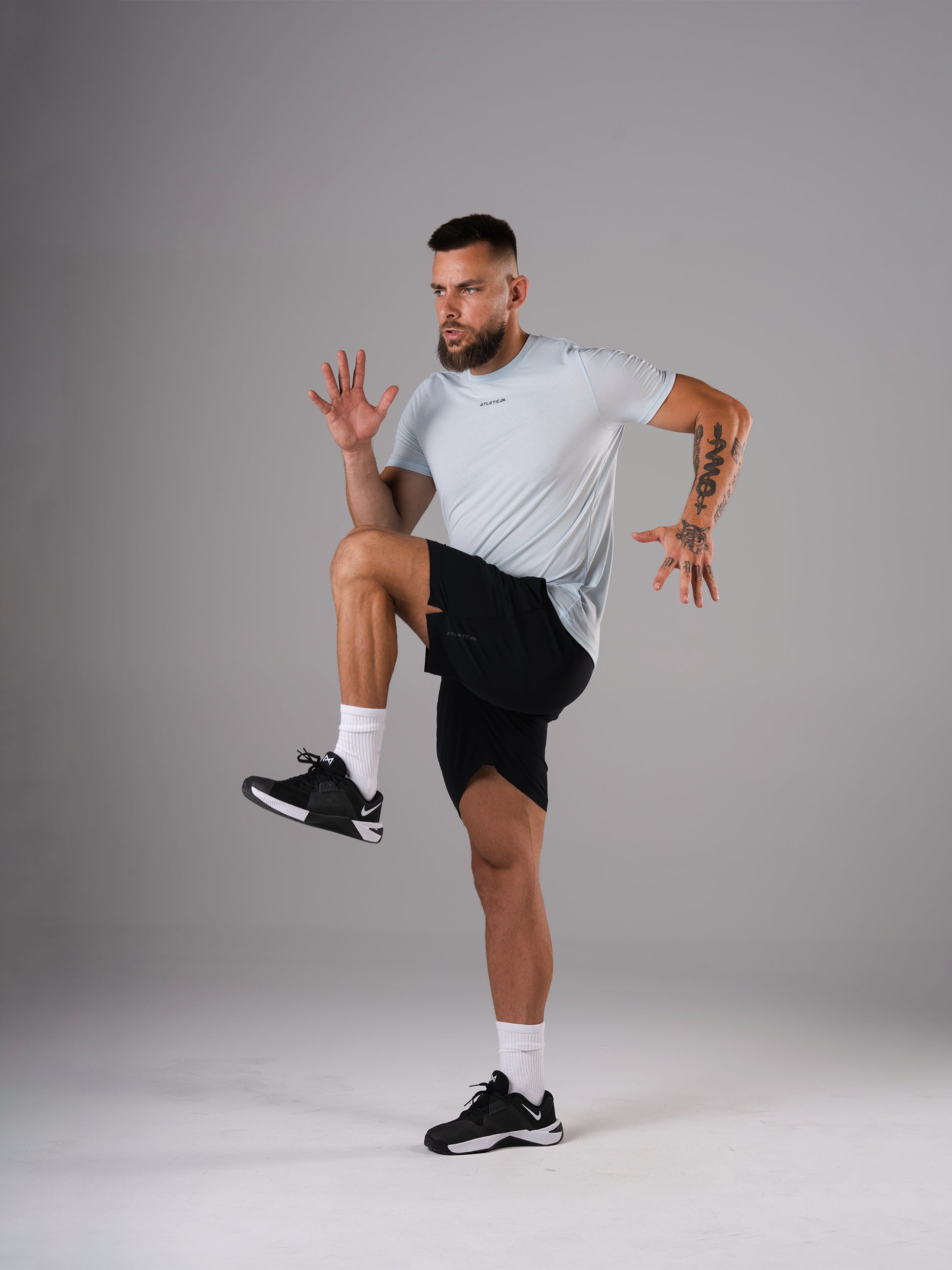 Mann in den schwarzen Flex Train Shorts von Atletica beim dynamischen Knieheben
