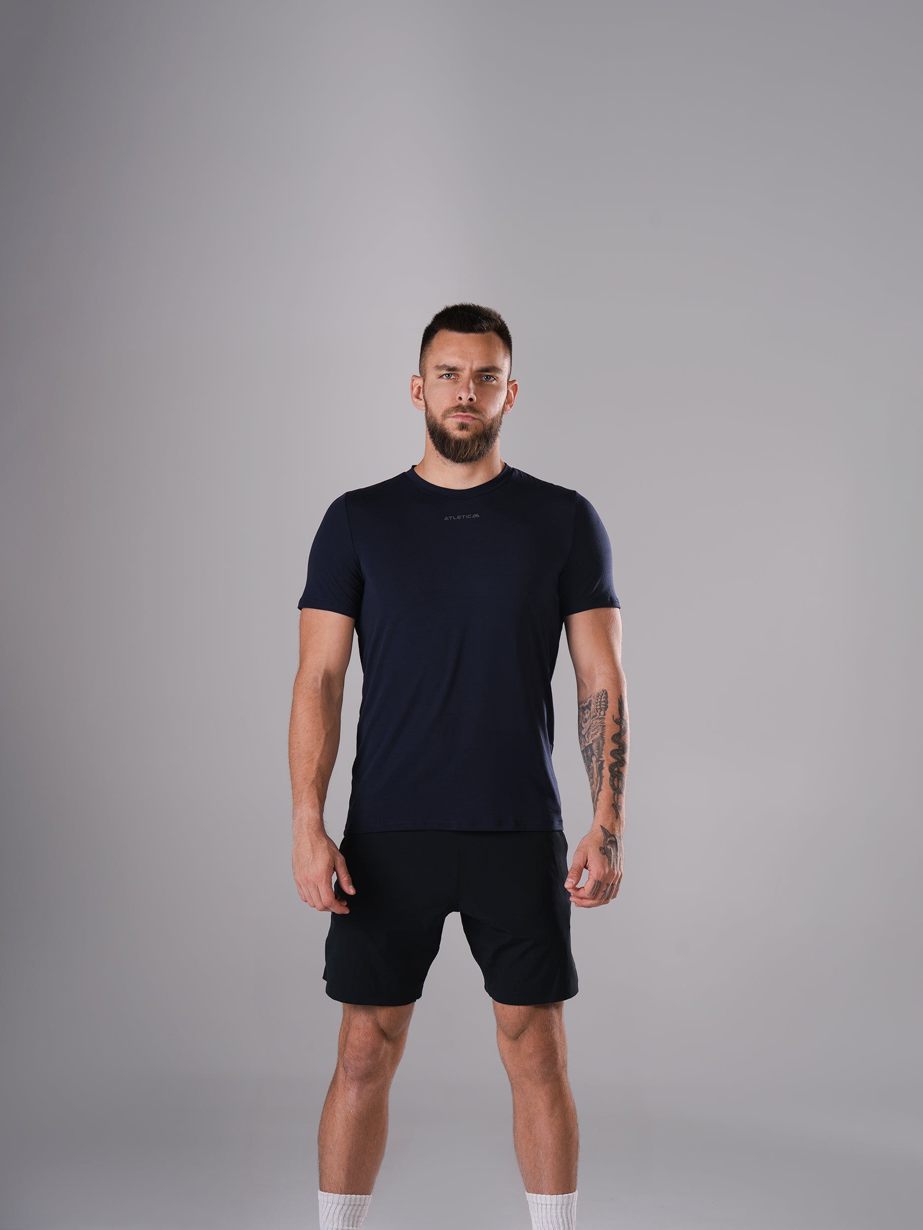 Mann im Flex Train T-Shirt in Dark Navy von Atletica mit schwarzen Shorts, Ganzkörperansicht