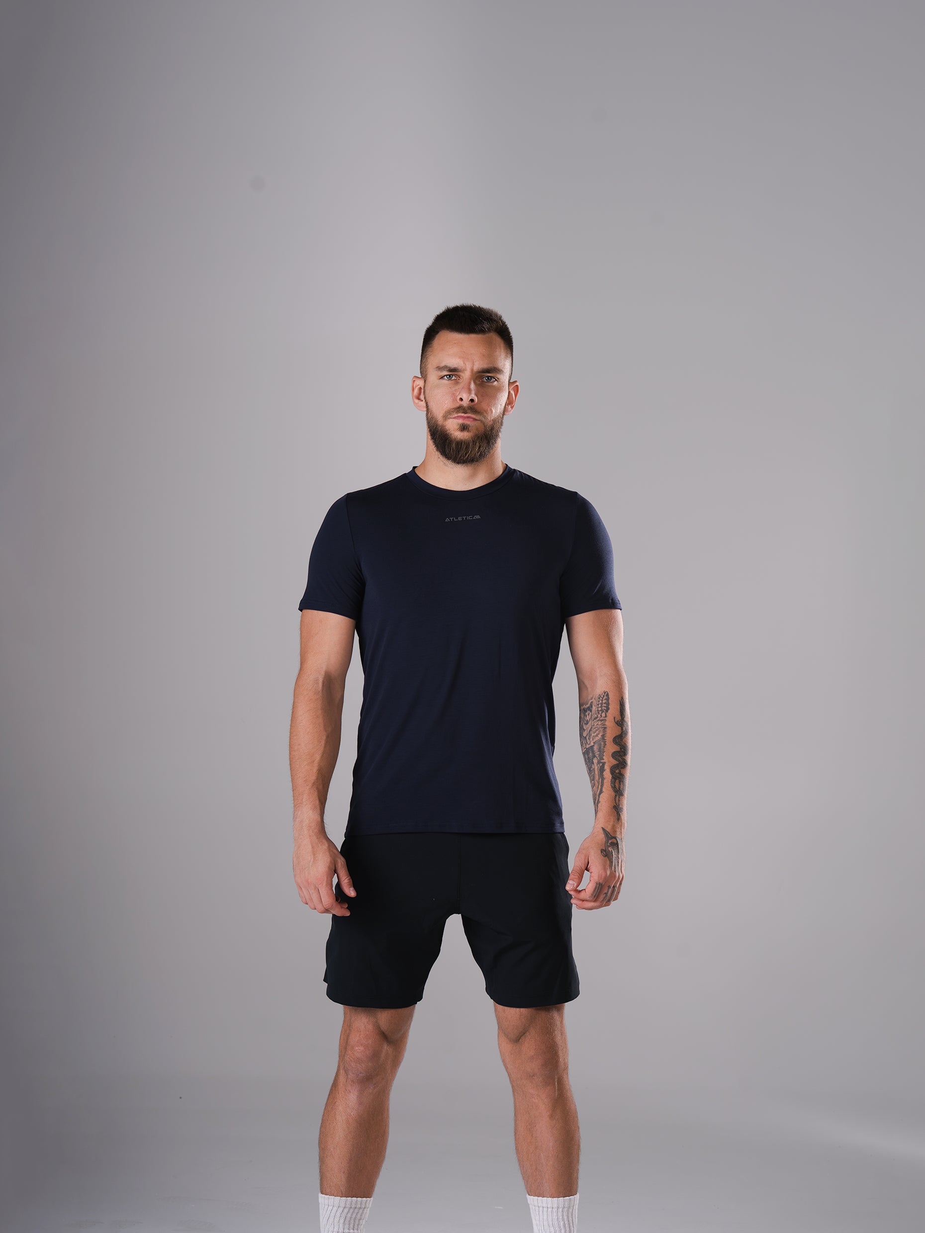 Mann im Flex Train T-Shirt in Dark Navy von Atletica mit schwarzen Shorts, Ganzkörperansicht