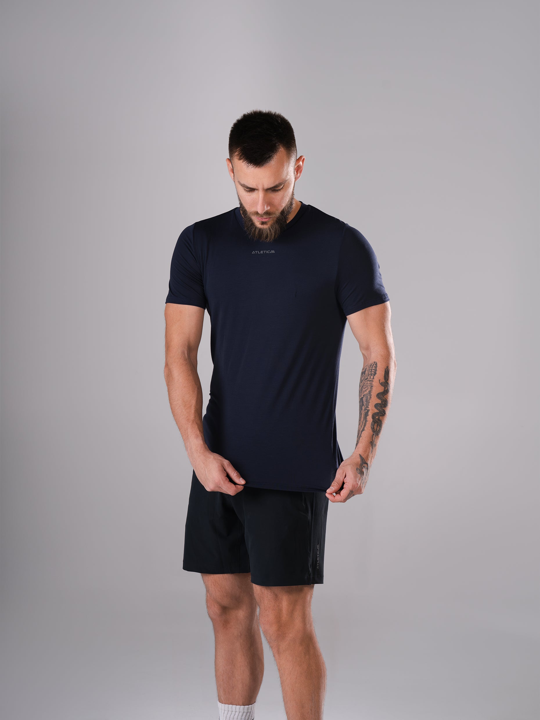 Mann zieht am Saum des Flex Train T-Shirt in Dark Navy von Atletica