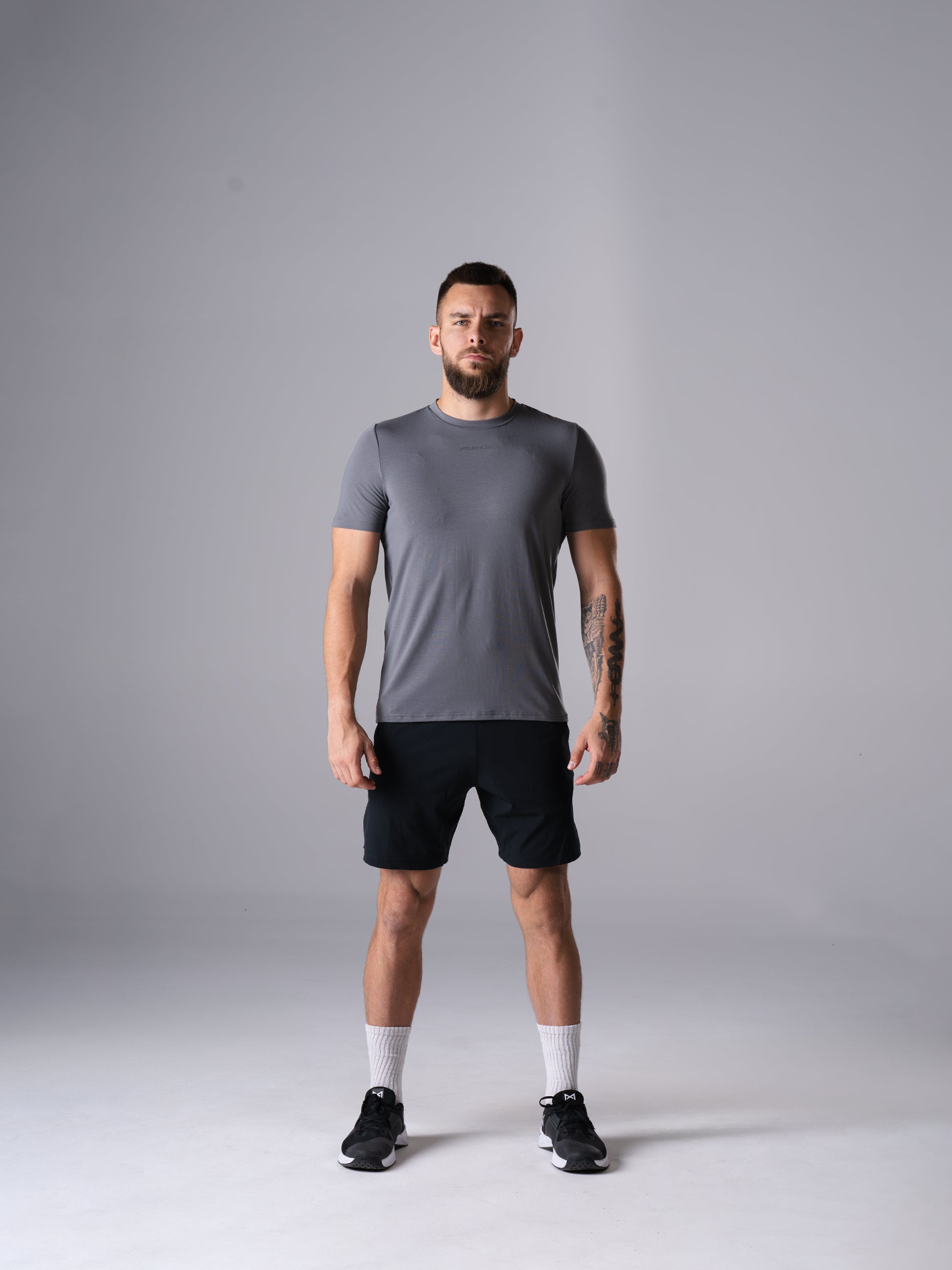 Ganzkörperansicht: Mann im Flex Train T-Shirt in CastleRock Grey von Atletica mit schwarzen Shorts