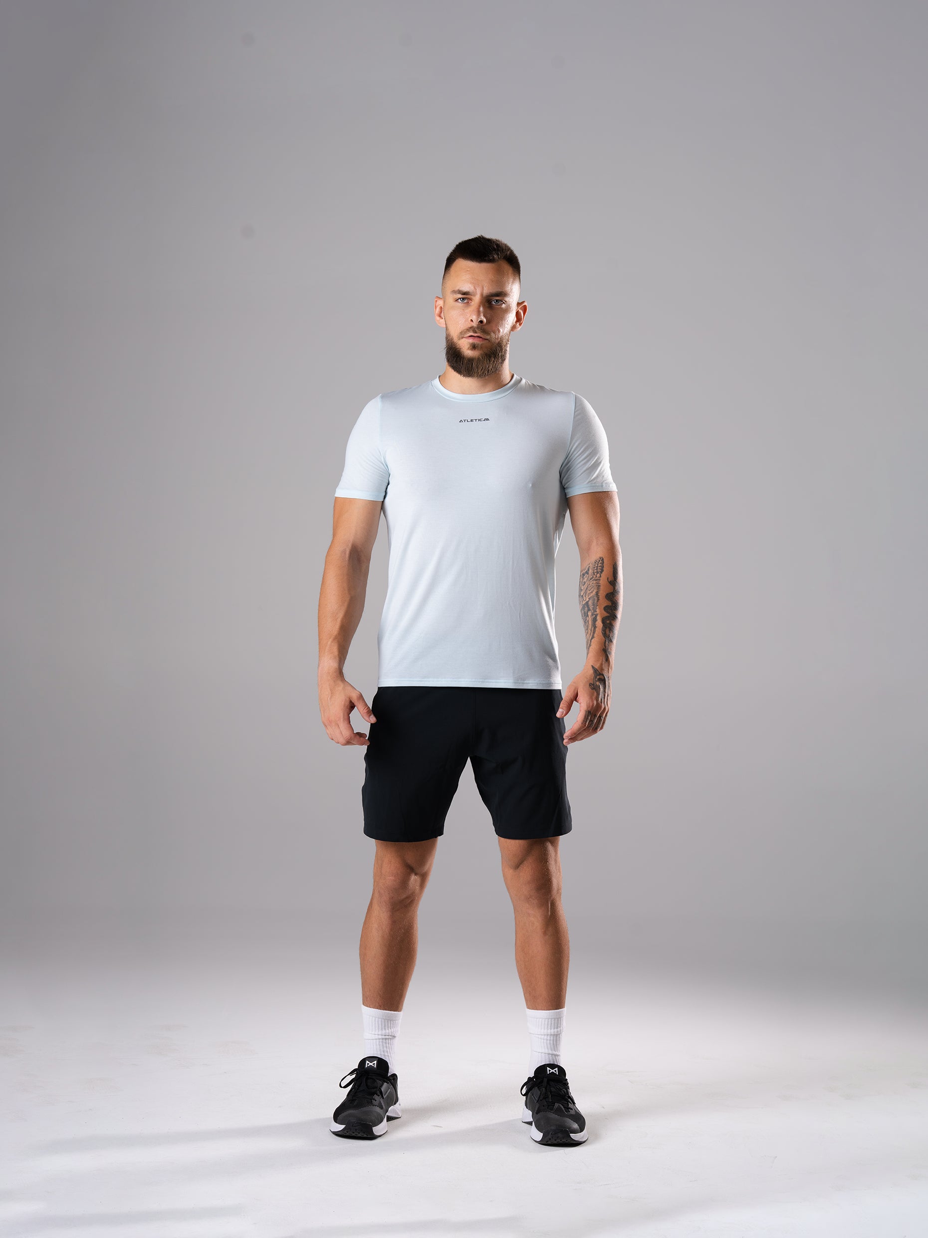 Mann im Flex Train T-Shirt in Ice Blue von Atletica mit schwarzen Flex Train Shorts, Ganzkörperansicht