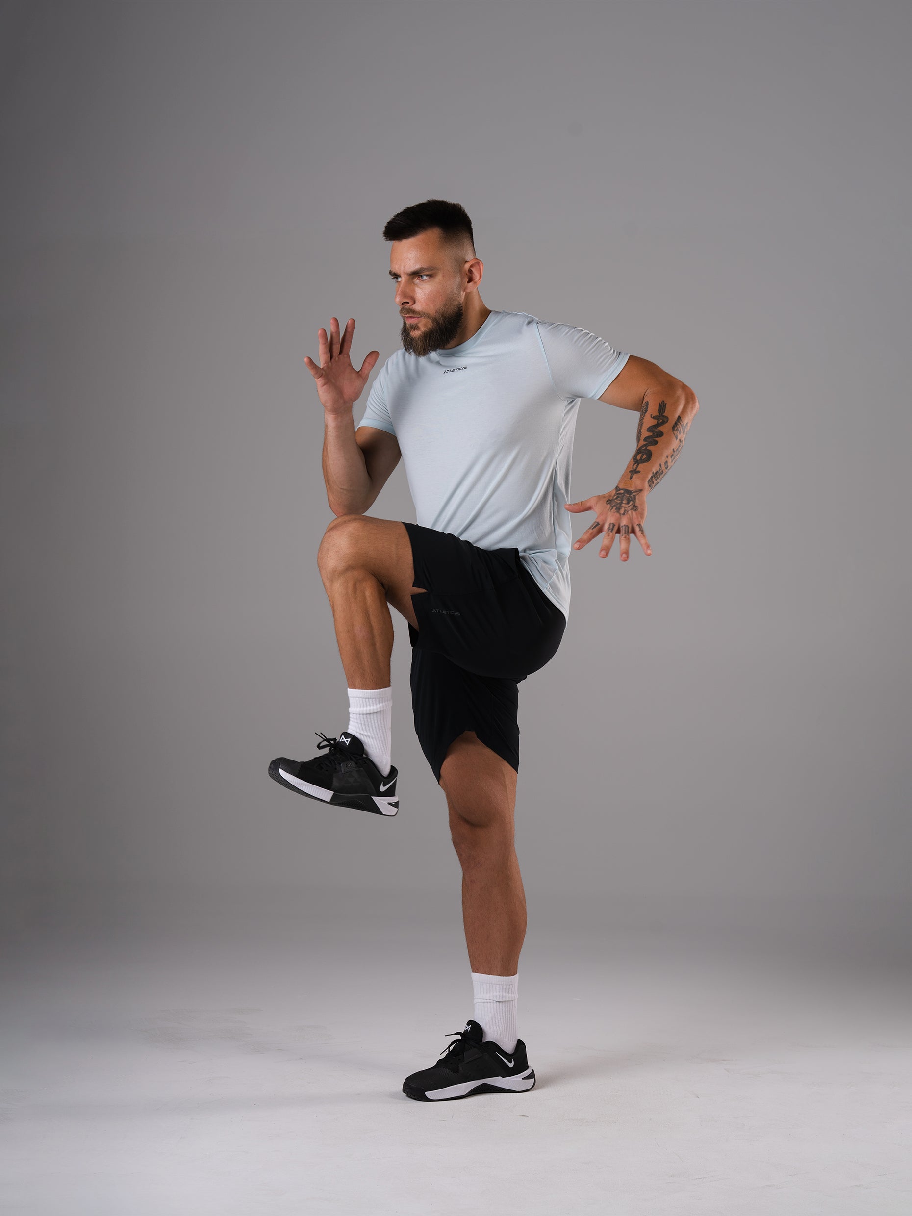 Mann im Flex Train T-Shirt in Ice Blue von Atletica beim dynamischen Knieheben