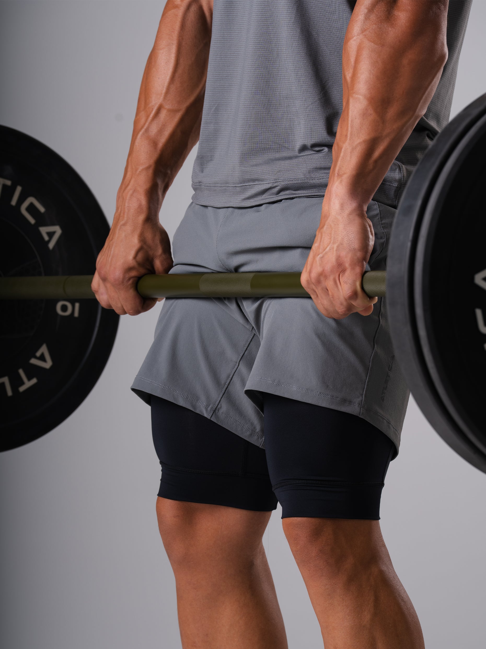 Mann in den Hard Lift Shorts in CastleRock Grey von Atletica hält eine beladene Langhantel beim Kreuzheben