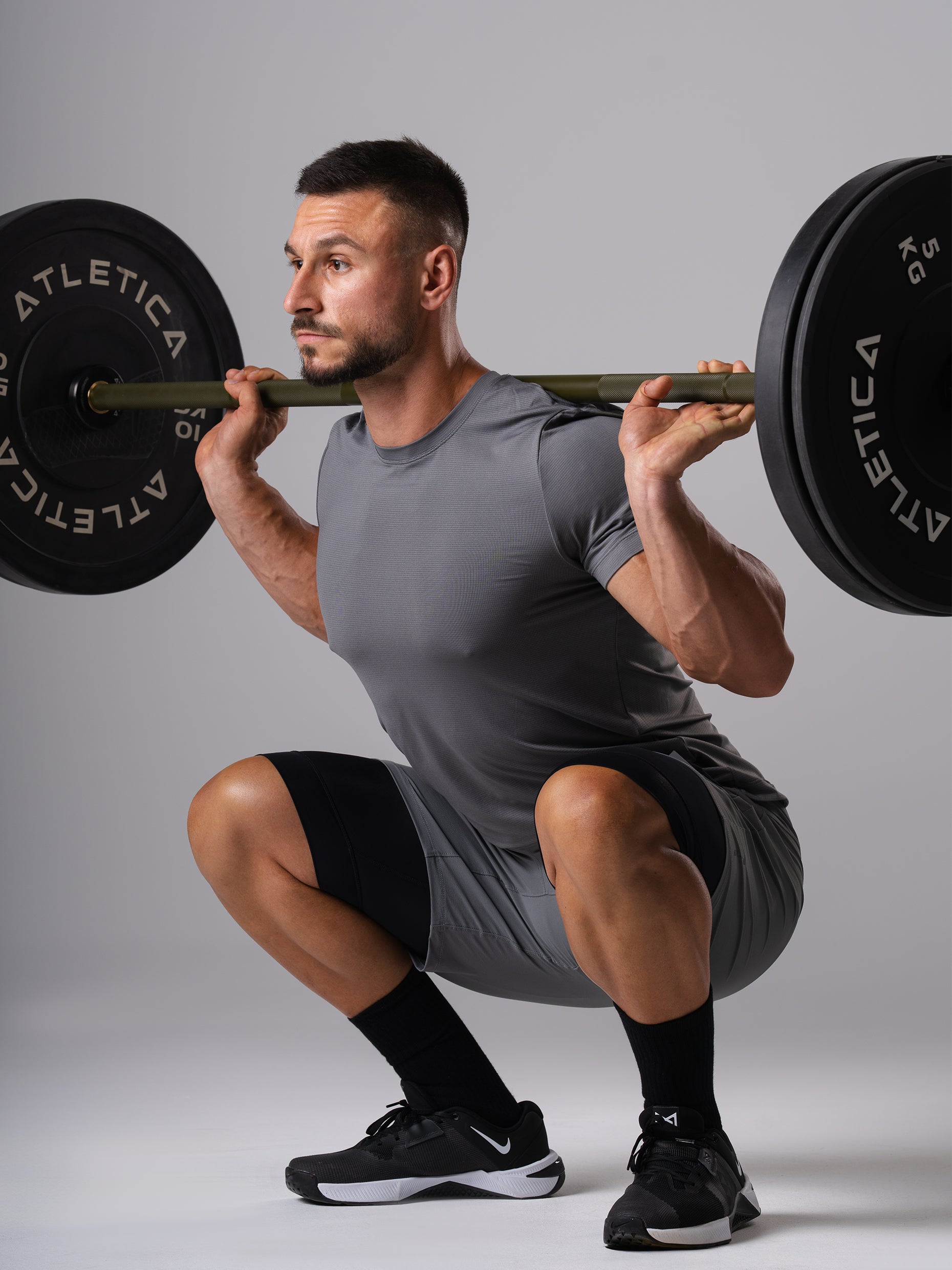 Mann in den Hard Lift Shorts in CastleRock Grey von Atletica bei der Kniebeuge mit Langhantel