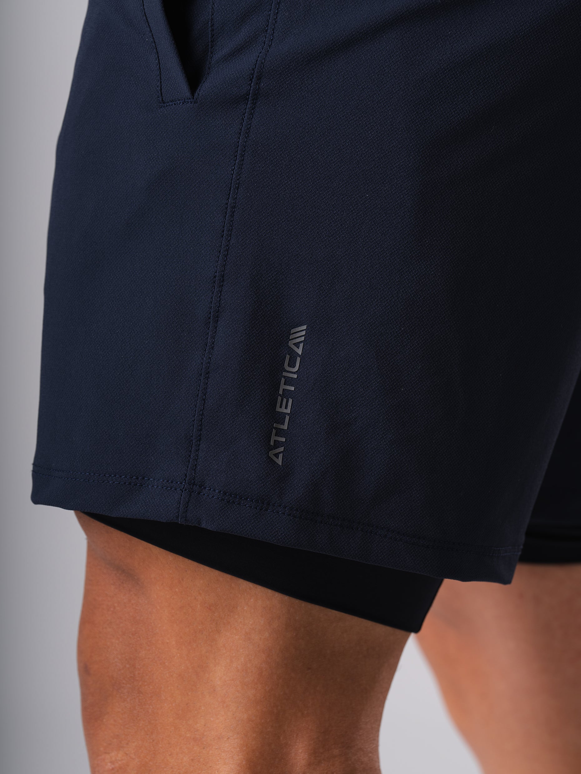 Seitliche Nahaufnahme der Hard Lift Shorts in Dark Navy von Atletica mit Logo am Bein