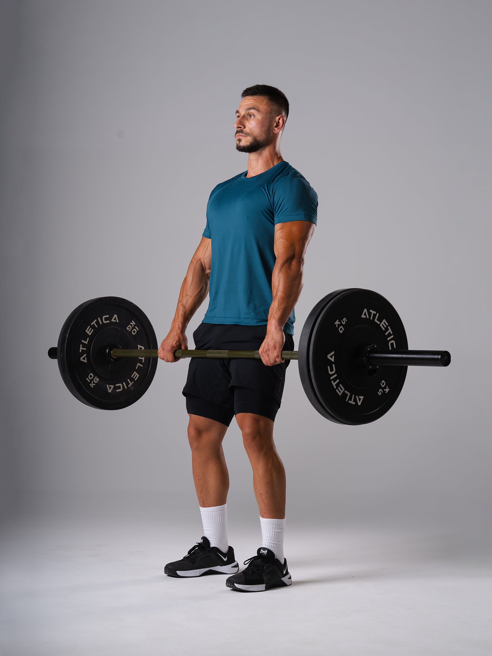 Mann im Hard Lift T-Shirt in Legion Blue von Atletica hält eine beladene Langhantel beim Kreuzheben