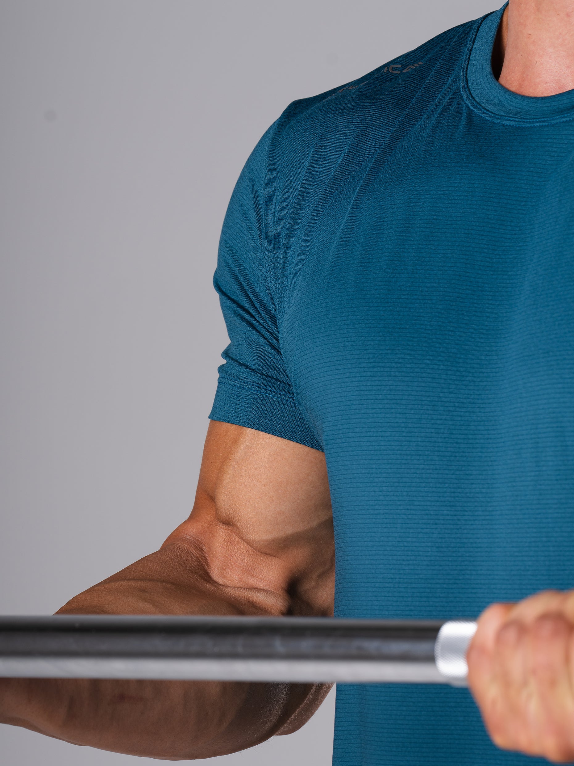 Nahaufnahme des Ärmels am Hard Lift T-Shirt in Legion Blue von Atletica beim Greifen einer Langhantel