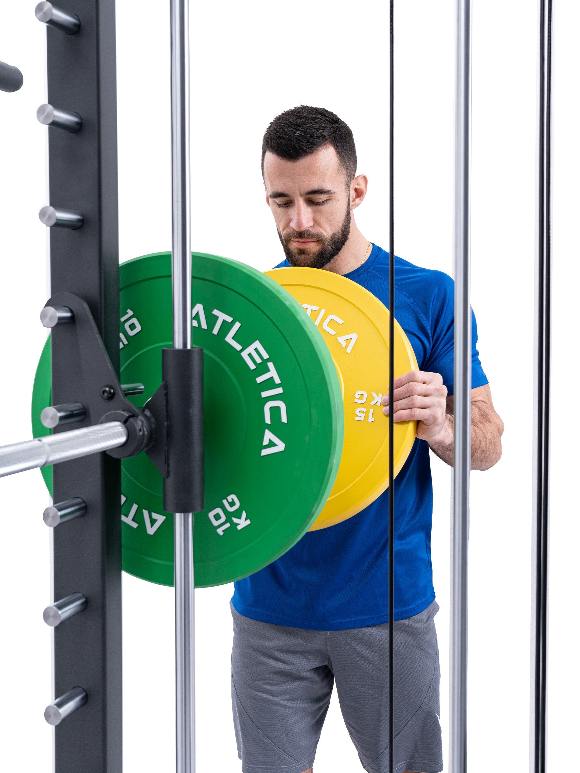 Athlet belädt das R8 Bradley Power Rack mit einer grünen 10 kg und einer gelben 15 kg Bumper Plate