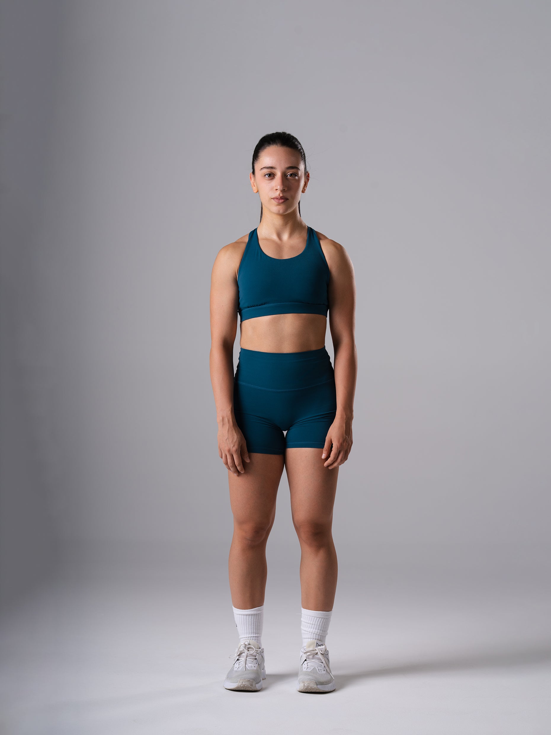 Frau in den Power Form Short Tights in Blue Lagoon von Atletica und Blue Lagoon Power Form Bra, Ganzkörperansicht