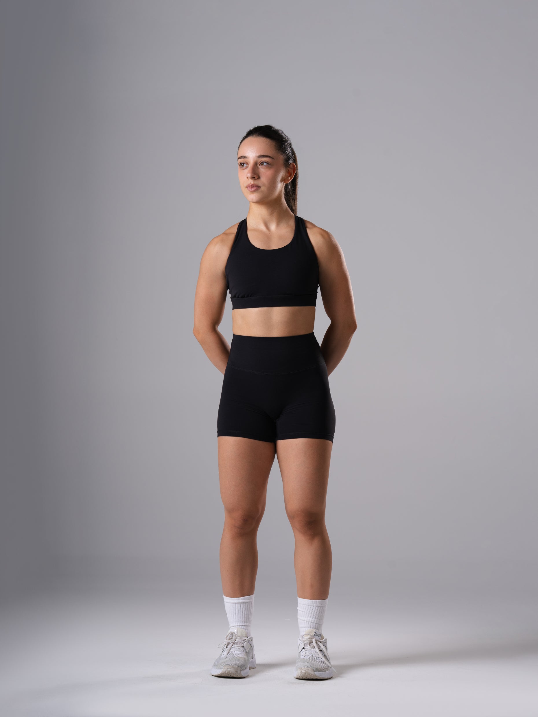 Ganzkörperansicht: Frau im Power Form Sports Bra in Schwarz von Atletica mit passenden Power Form Shorts in Schwarz