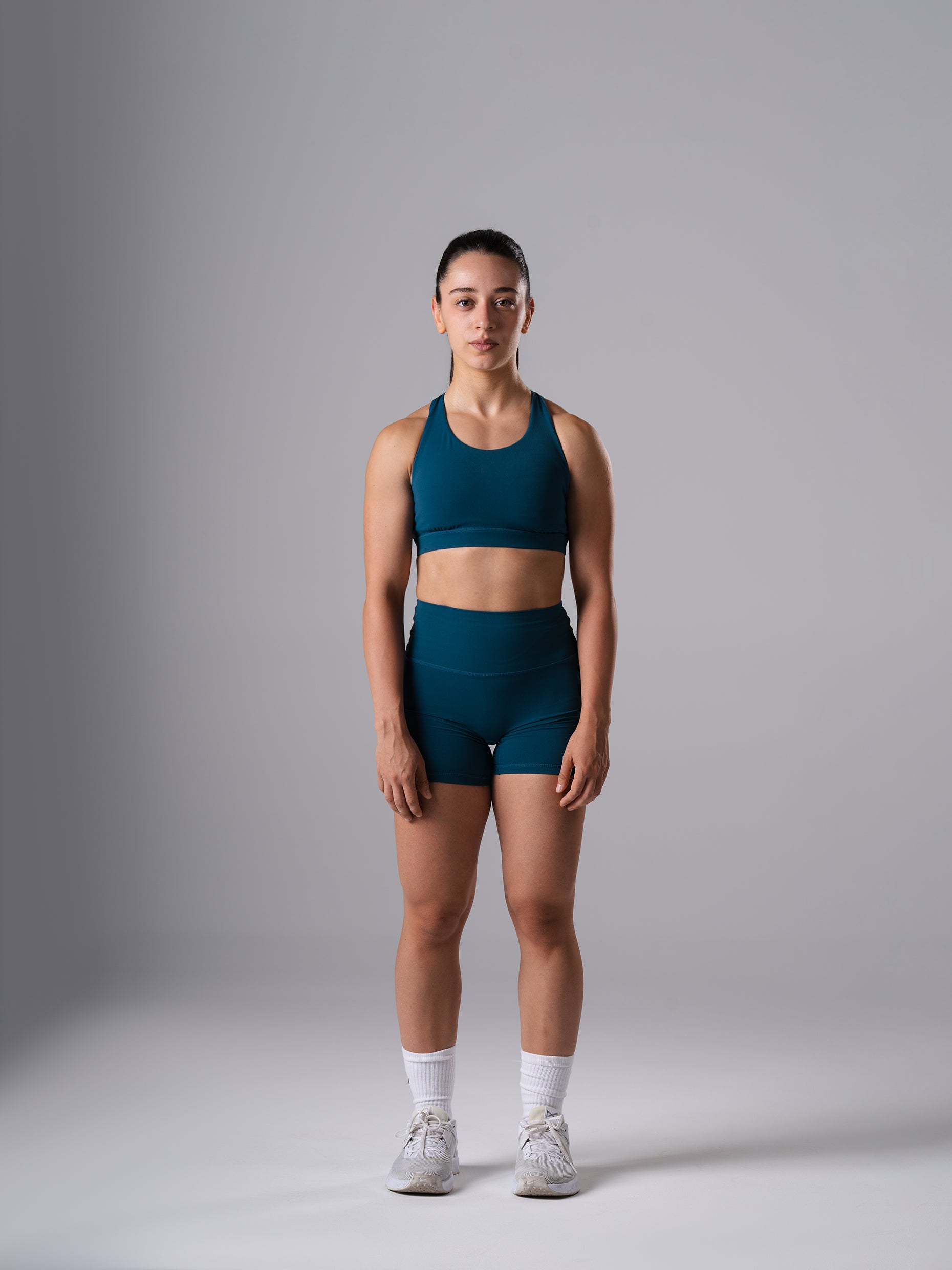 Frau im Power Form Sports Bra in Blue Lagoon von Atletica mit passenden Shorts, Ganzkörperansicht